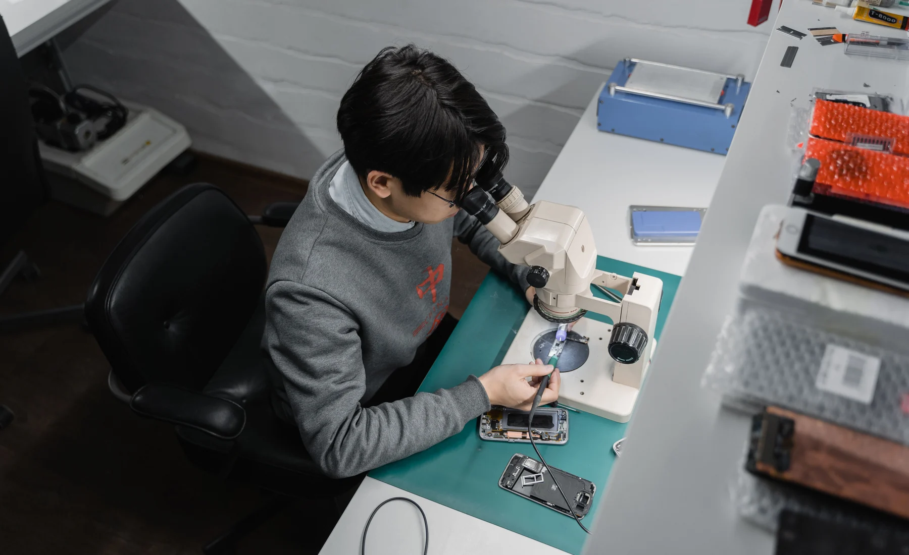 Mobile phone technician using a microscope during repair