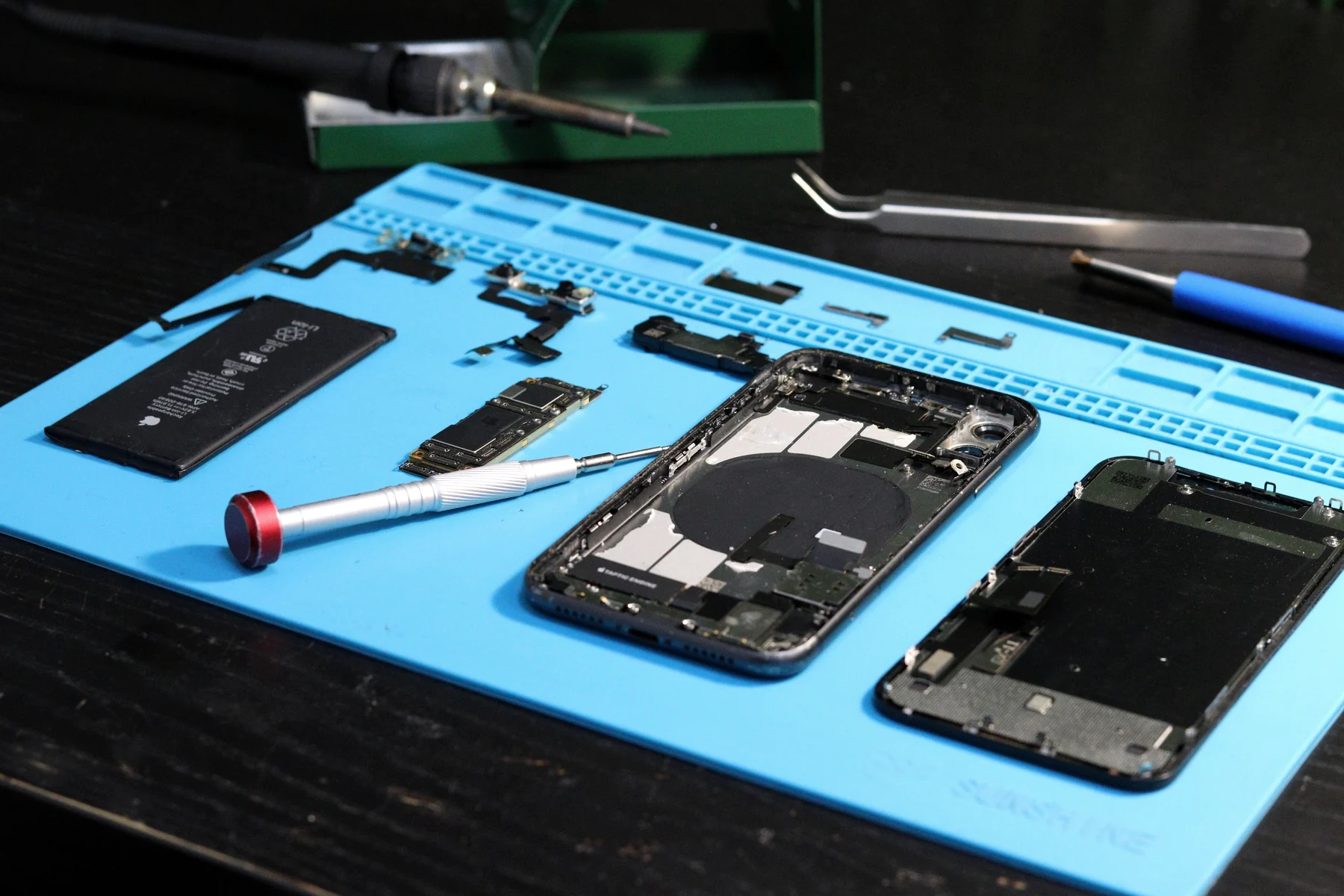 Disassembled iPhone components on a professional repair bench